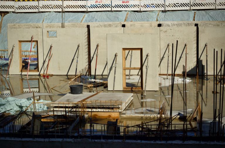 Geschalte Stahlbetonwand mit ausgesparten Fenster und Türöffnungen, Bewehrung steht heraus